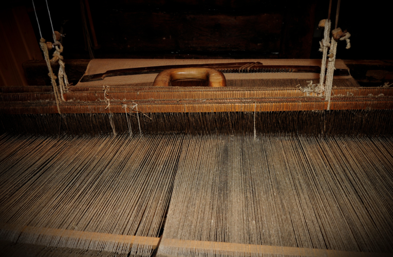 Various materials and tools used in tapestry weaving, including yarn, needles, and a loom.
