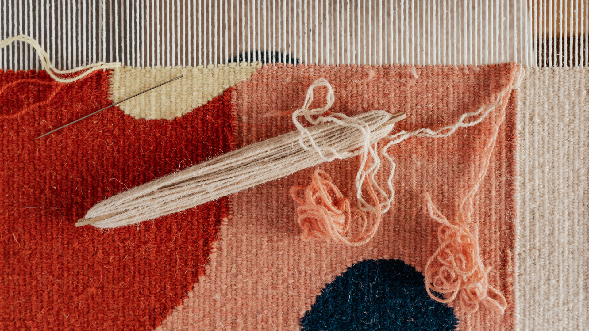 A close-up view of a weaver's loom with colorful threads and intricate patterns in progress.